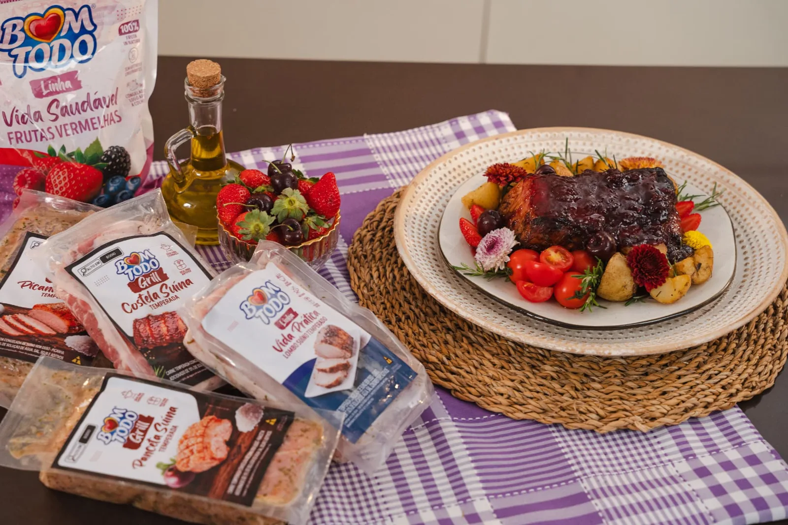 Produtos Bom Todo dispostos em uma mesa ao lado de um prato de carne suína preparada